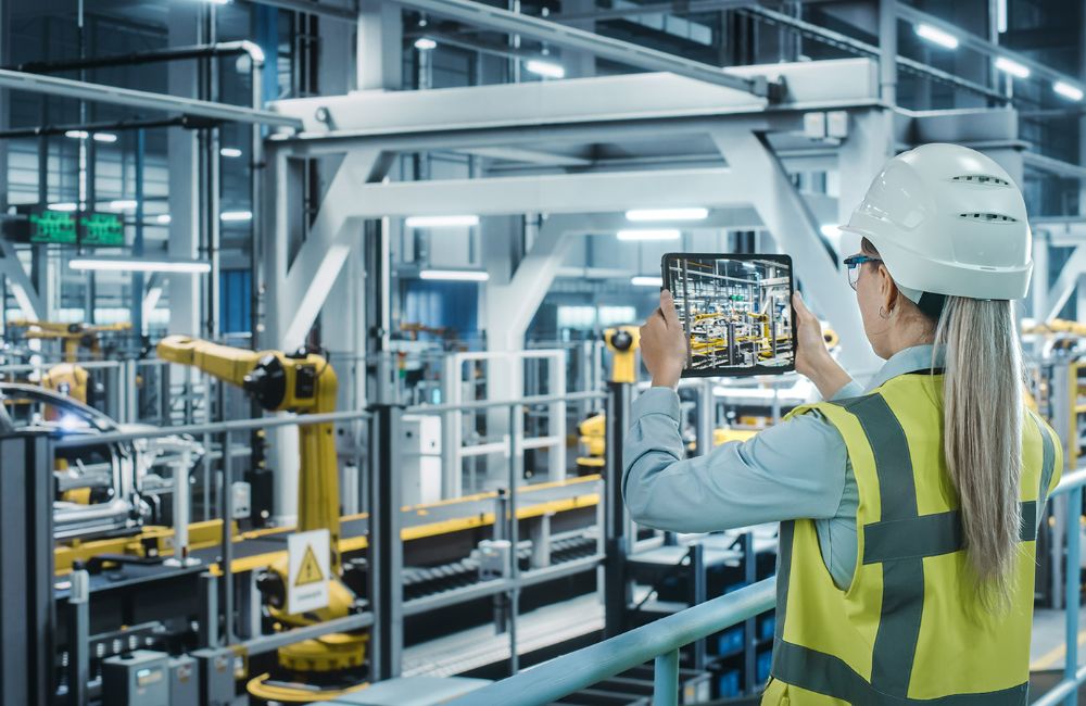 woman in hard hat uses tablet to scan machine safety features of manufacturing line